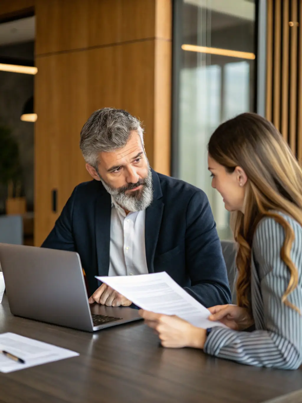 A business coach reviewing financial reports and performance metrics with an SME owner, focusing on improving business performance.